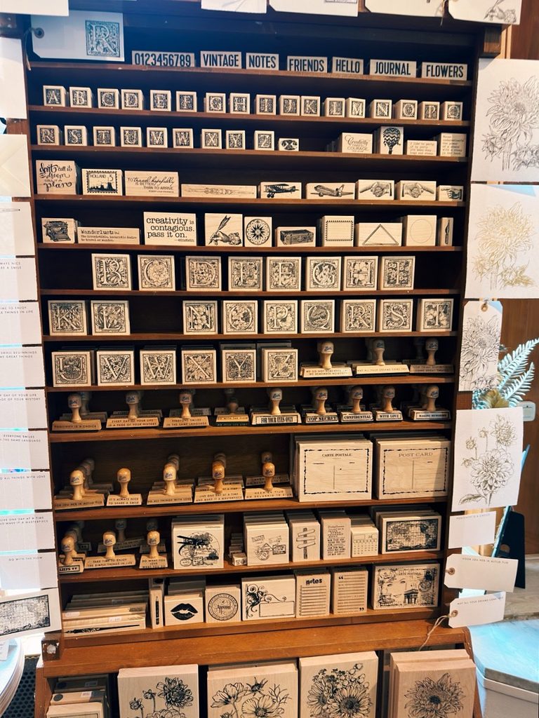Wooden shelves in Amsterdam filled with rows of rubber stamps featuring alphabet letters, vintage icons, and floral patterns