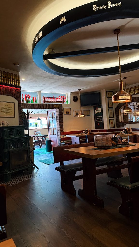 Bizon Pub Bratislava interior with wooden tables benches and a large circular ceiling sign