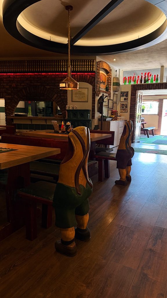 Interior of Bizon Pub Bratislava featuring wooden tables and unique chairs carved to look like people bending over