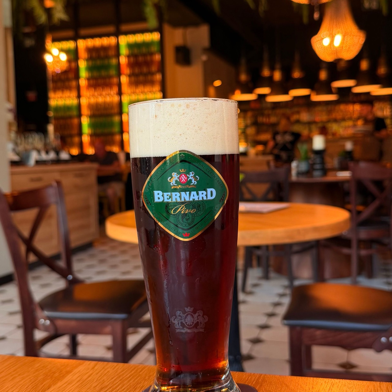 Glass of golden wheat beer with logo and Czech text NAL CEECH CAGE BERNARD Pivo