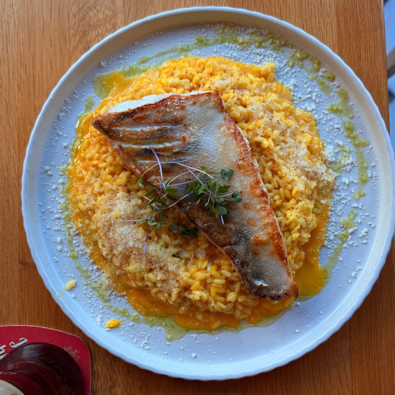 Plate of rice garnished with herbs and sauce on a wooden table at Brejk Bistro Prešov, with a sign in the background