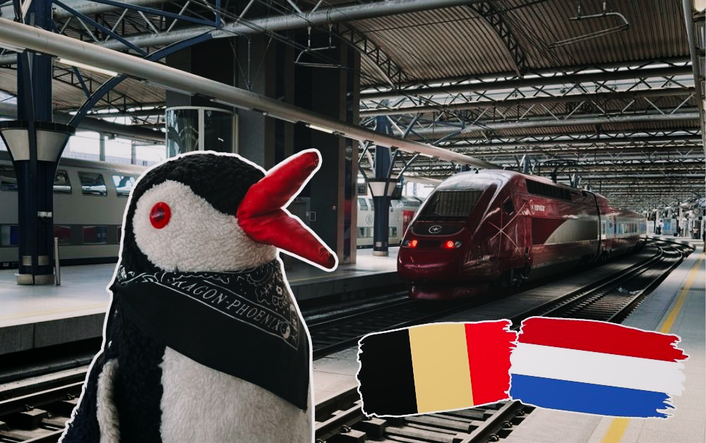 Miško stands in a train station with flags of Brussels and Amsterdam beside a red train