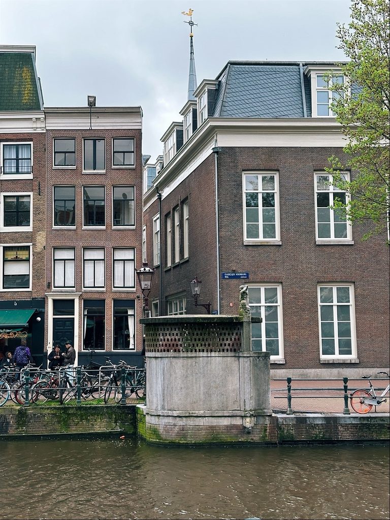 A canal in Amsterdam with bicycles parked along the side and buildings lining the waterway