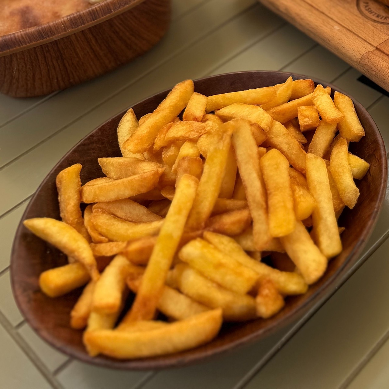 Golden french fries served in a wooden bowl at Restaurant Familjar Pashtriku Prizren