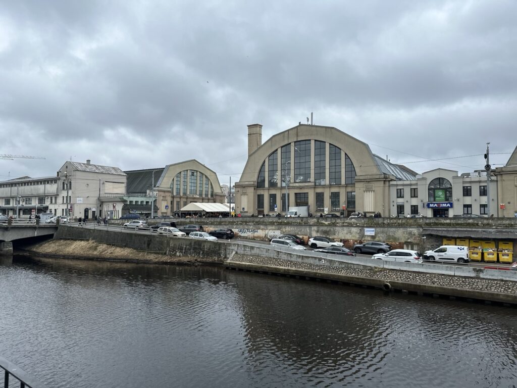 Riga Central Market interior with bustling stalls, fresh produce and a sign