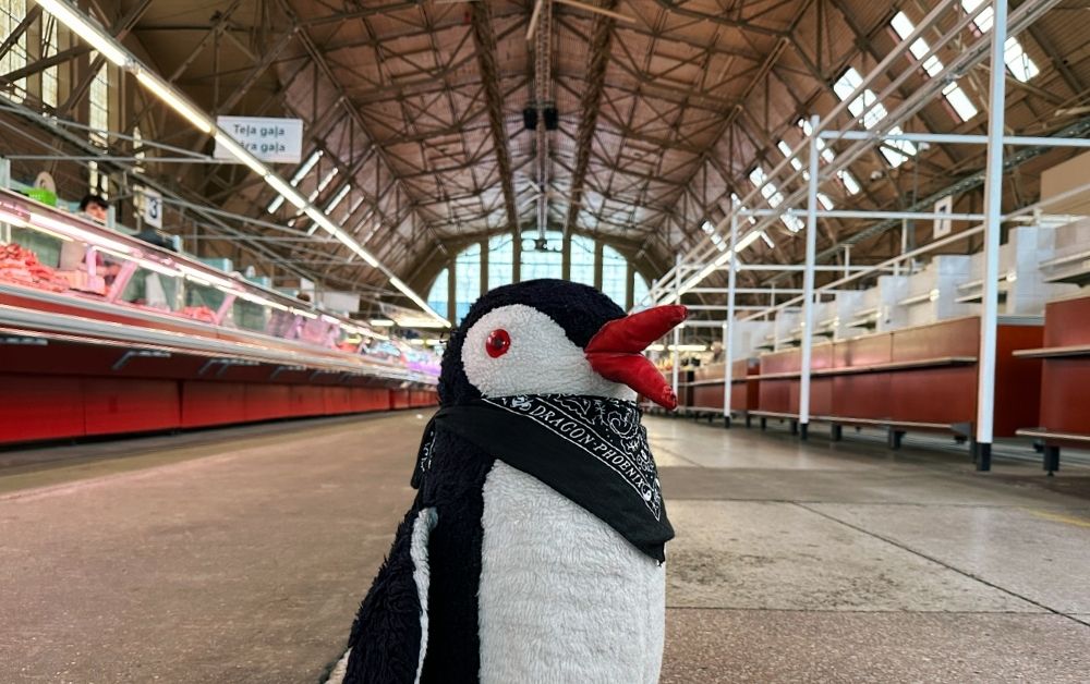 A penguin perched beside a sign at Riga Central Market