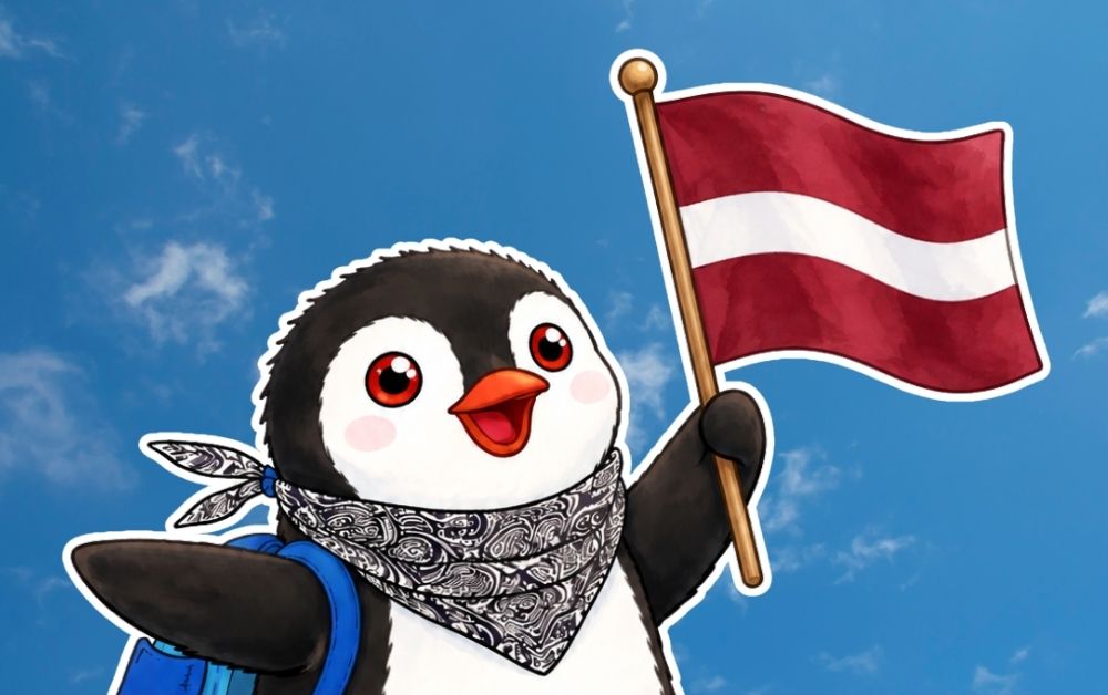 Miško the knitted penguin with a bandana holding the flag of Latvia against a blue sky