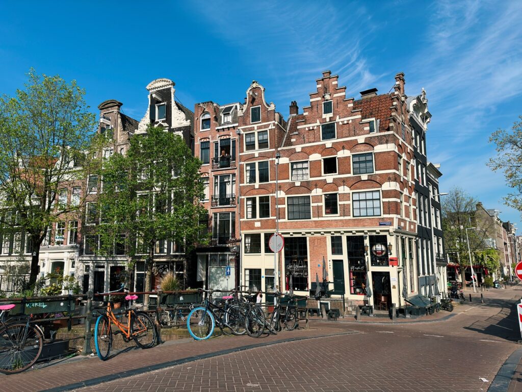 Traditional brick buildings with stepped gables and bicycles parked along the street in the Netherlands under a blue sky