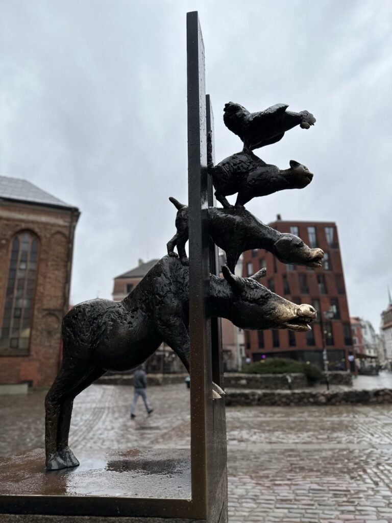 Bronze sculpture of the Bremen Town Musicians showing a donkey dog cat and rooster climbing a wall in Riga