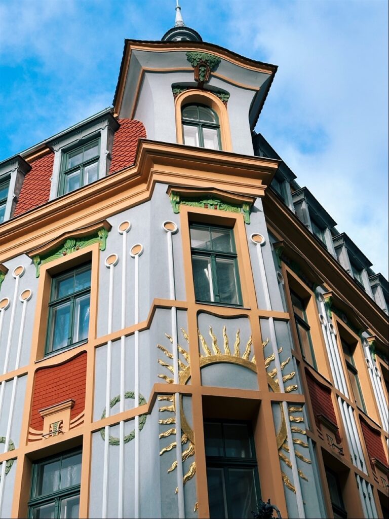 Ornate Art Nouveau building facade in Riga with a golden sun relief and orange and grey decorative elements