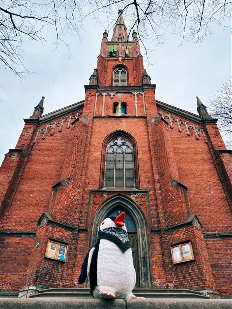 Tall church with spire and steeple in Riga, Latvia, with a sign nearby