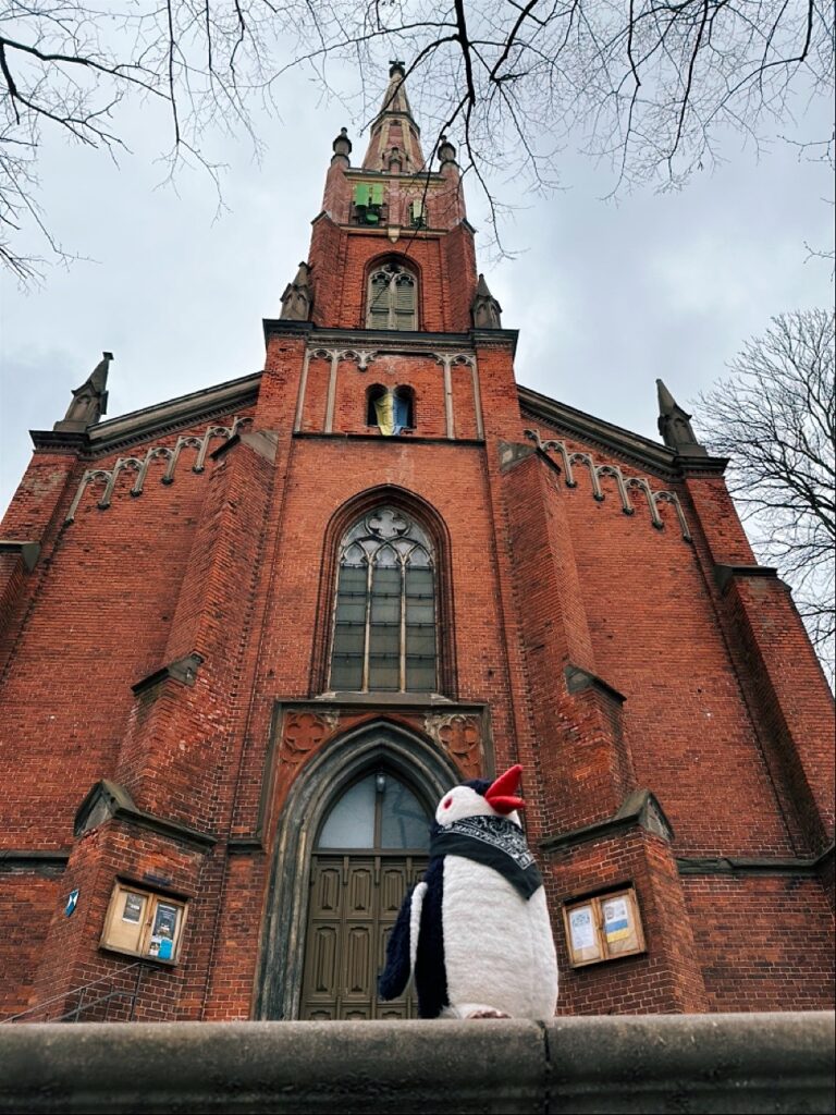 A historic church in Riga with a tall steeple and spire rising above its stone façade