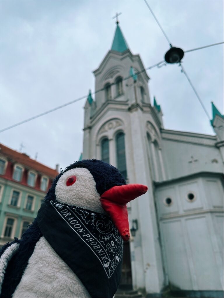 Penguin statue in front of Riga Castle with a sign nearby
