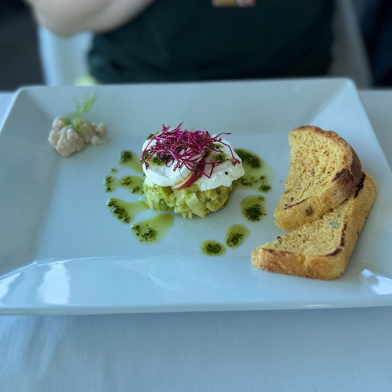 White square plate with a dish featuring green oil, red microgreens, a creamy topping and two slices of toast at VEŽA Bratislava