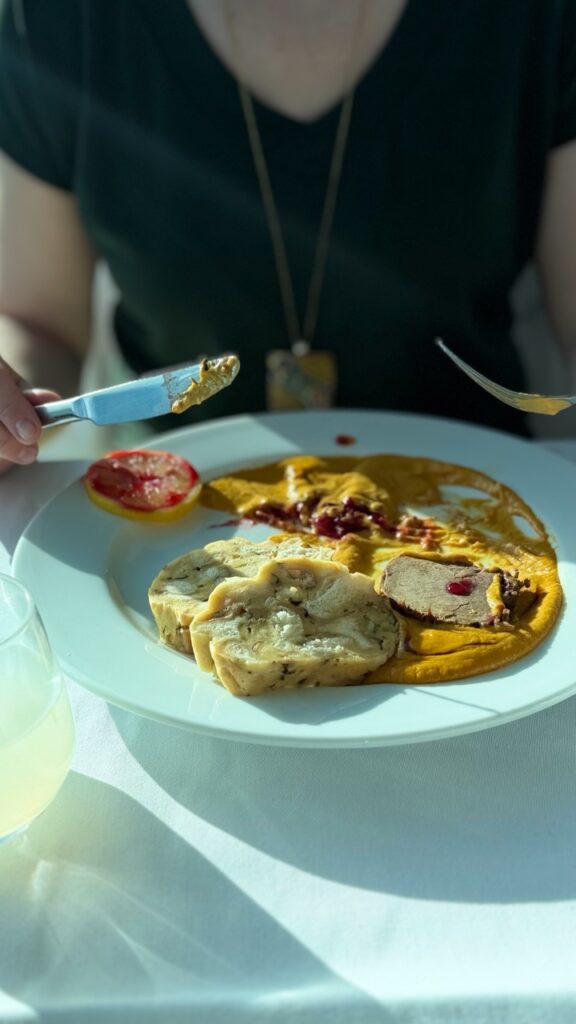 Slices of meat and terrine with yellow sauce and berries on a white plate at VEŽA Bratislava