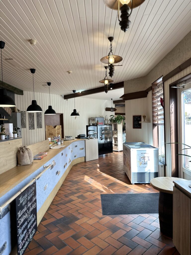Restaurant interior with wooden floor, ceiling light fixture and a menu board listing hot drinks