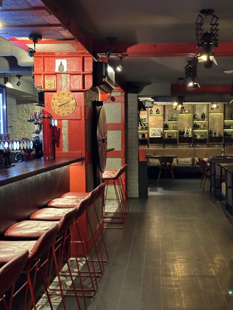 Restaurant interior with low ceiling, pendant light fixture, bar counter, wooden chairs and a sign