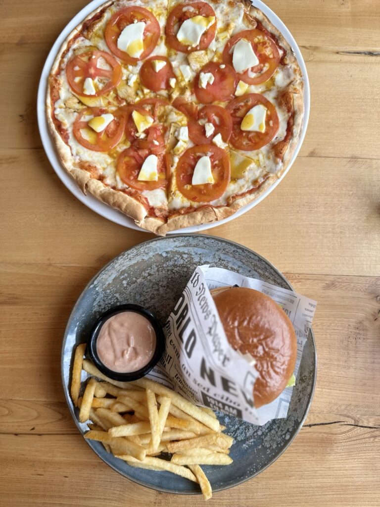 A plate of fast-food style comfort dishes on a table beside a restaurant sign