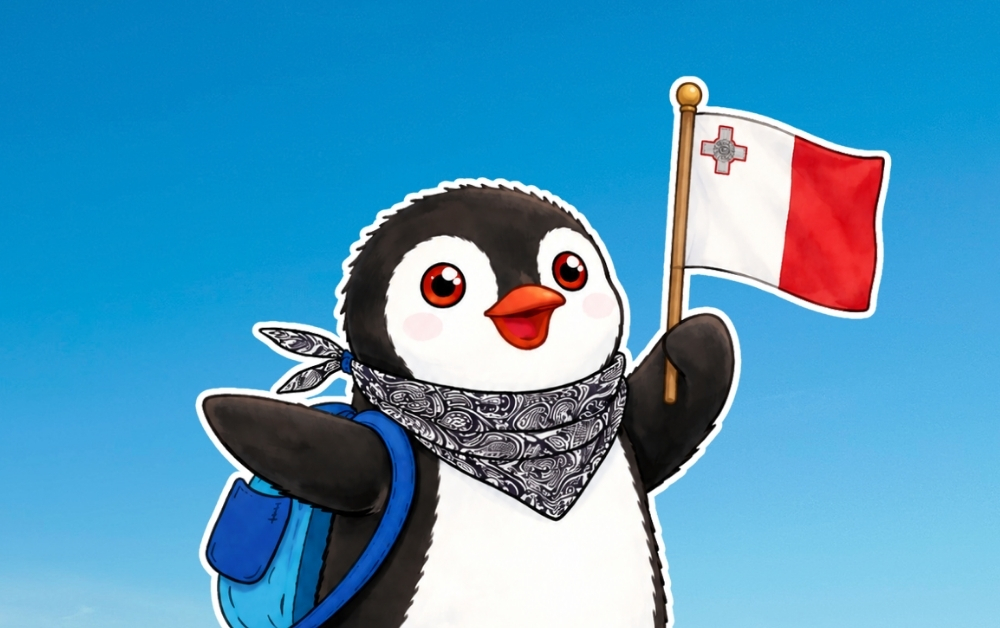Miško the penguin wearing a backpack and patterned bandana holding the flag of Malta against a blue sky
