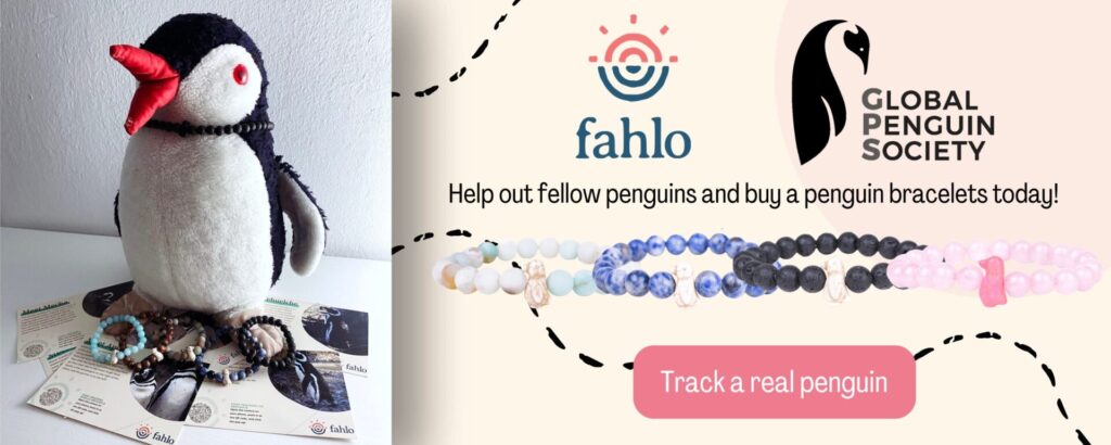 Plush penguin Miško next to a promotional banner for Fahlo penguin tracking bracelets