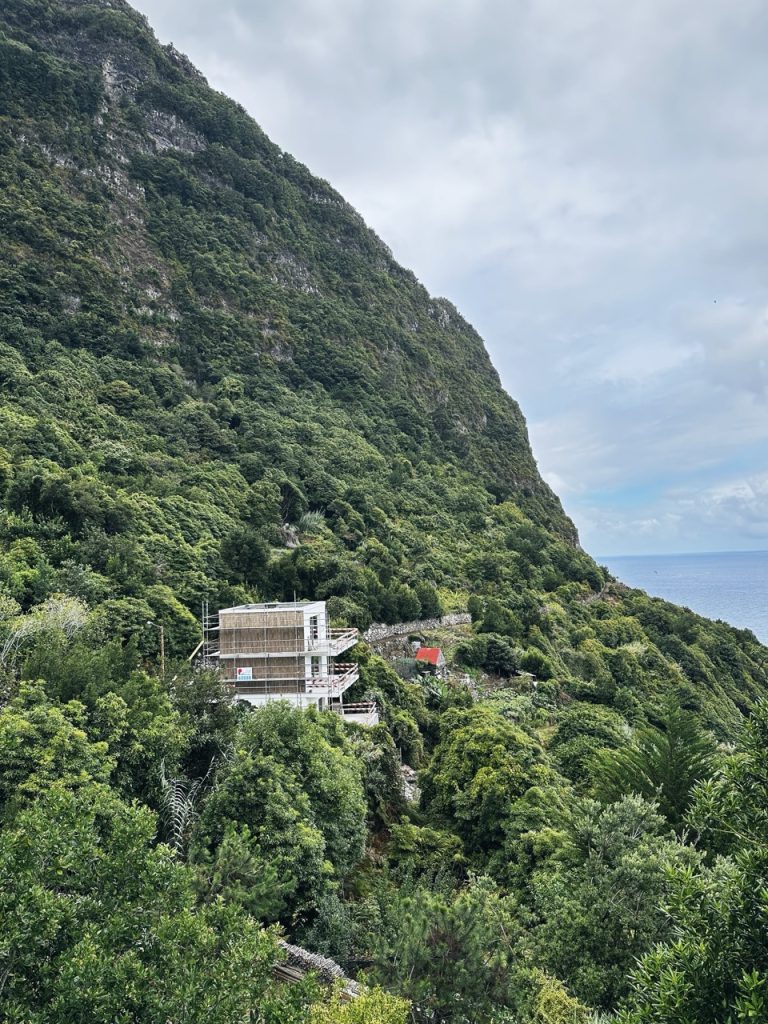 A building under construction sits on a lush green hillside in Madeira