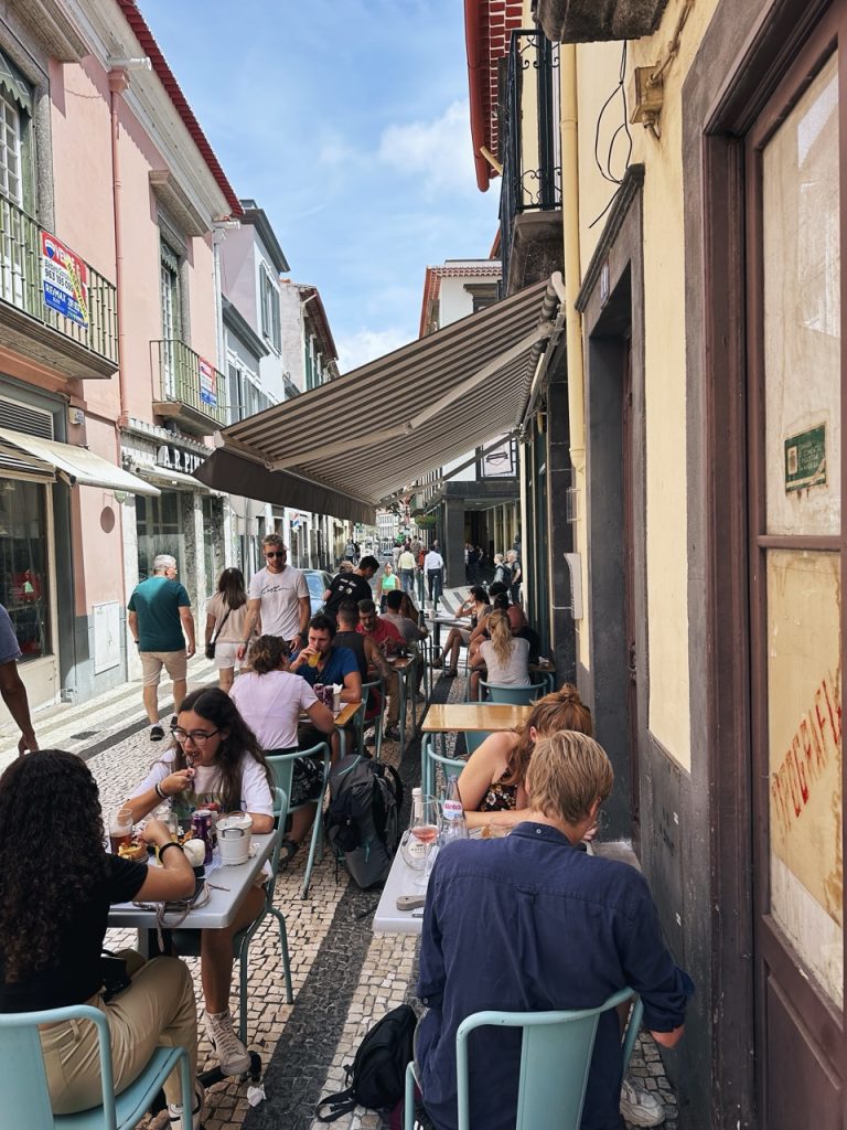 People dine at outdoor tables along a narrow street in Madeira