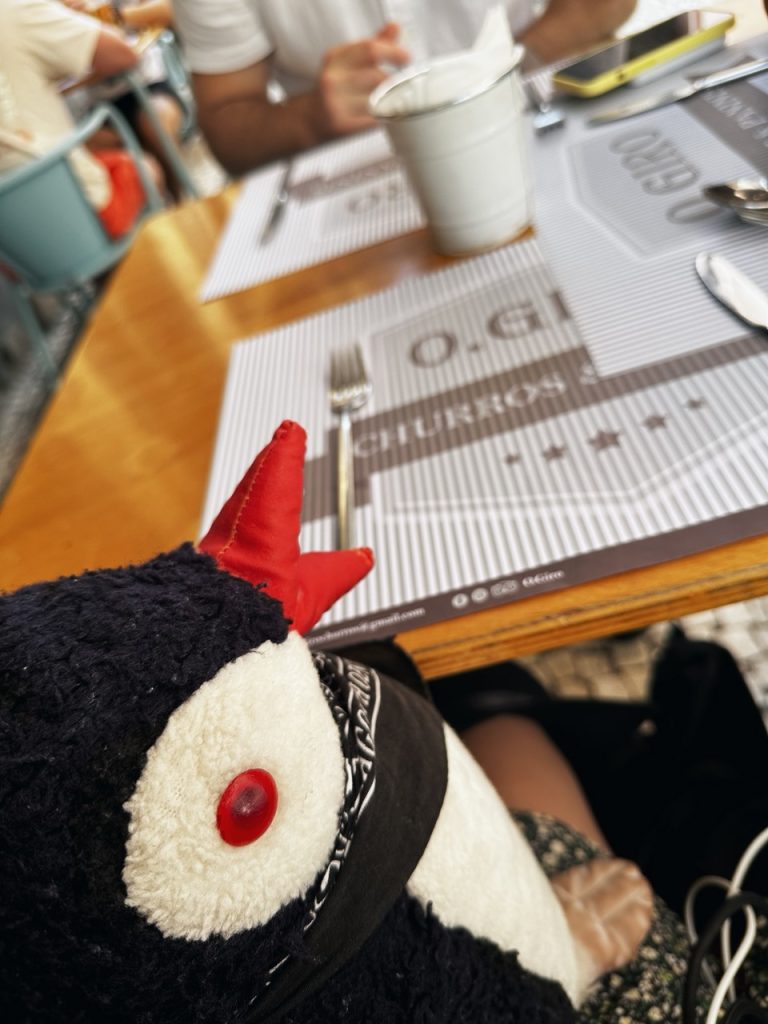 A plush penguin toy sits at a restaurant table in Madeira