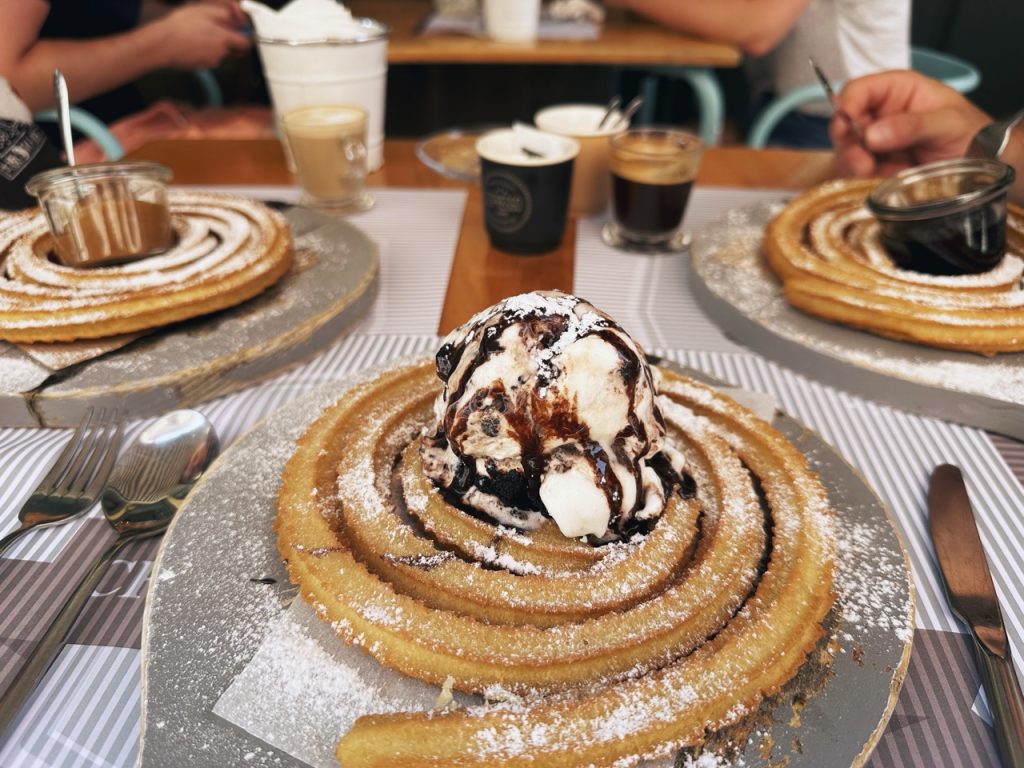 Spiral churros topped with ice cream and chocolate sauce on a restaurant table