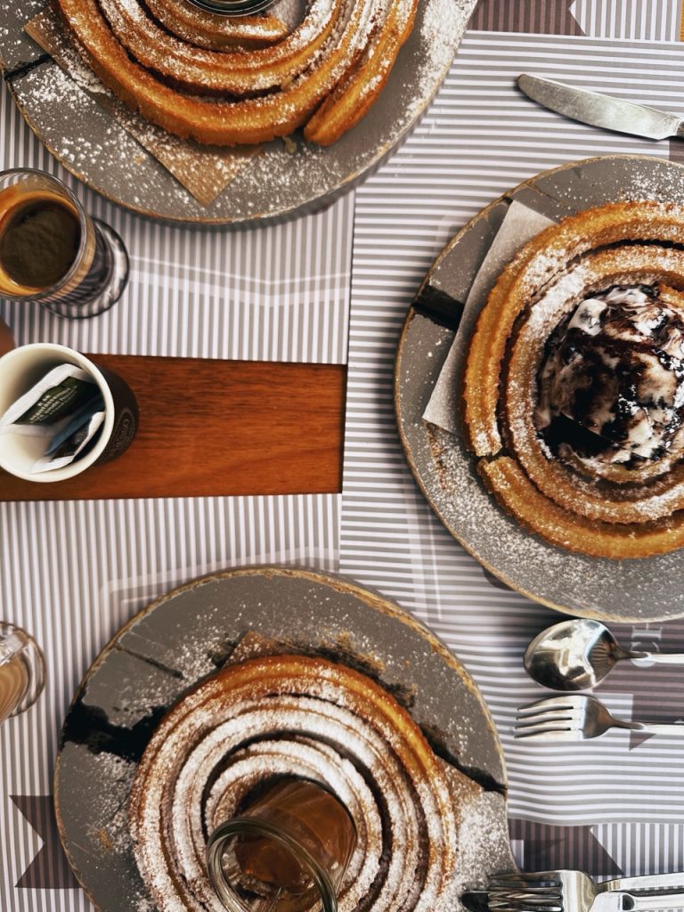Three plates of spiral churros with different toppings and coffee in Madeira