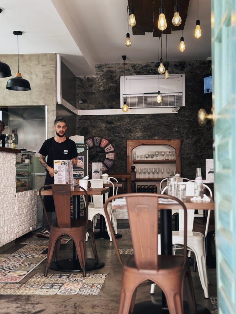 A server stands in a rustic restaurant with stone walls and hanging lights