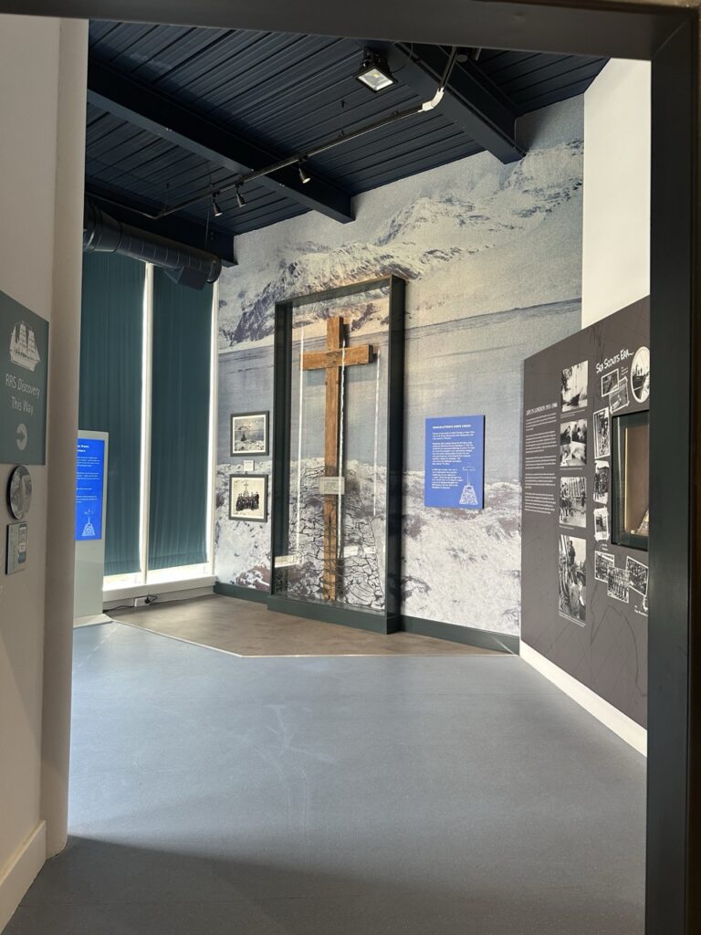 Large wooden cross displayed in a museum exhibit about RRS Discovery