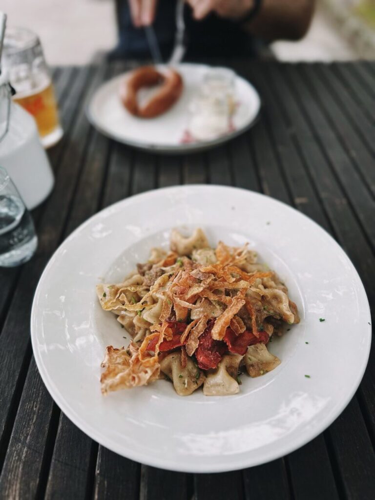A plate of pasta topped with crispy fried onions and red garnish