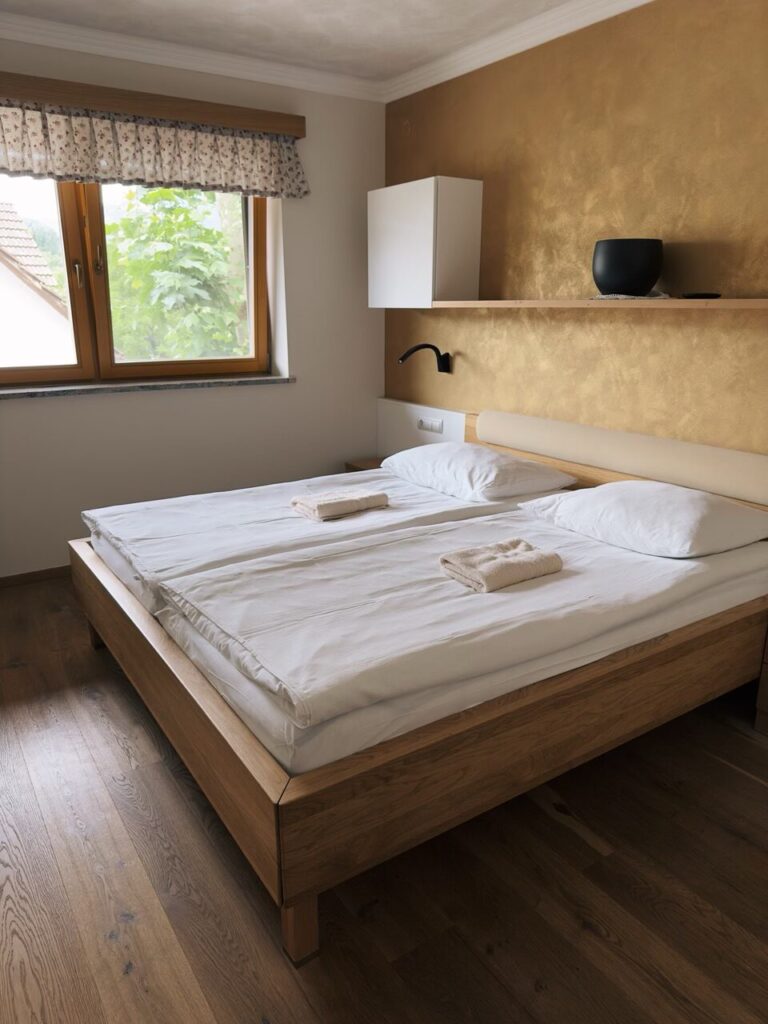 A wooden bed with white linens sits in a room with gold walls
