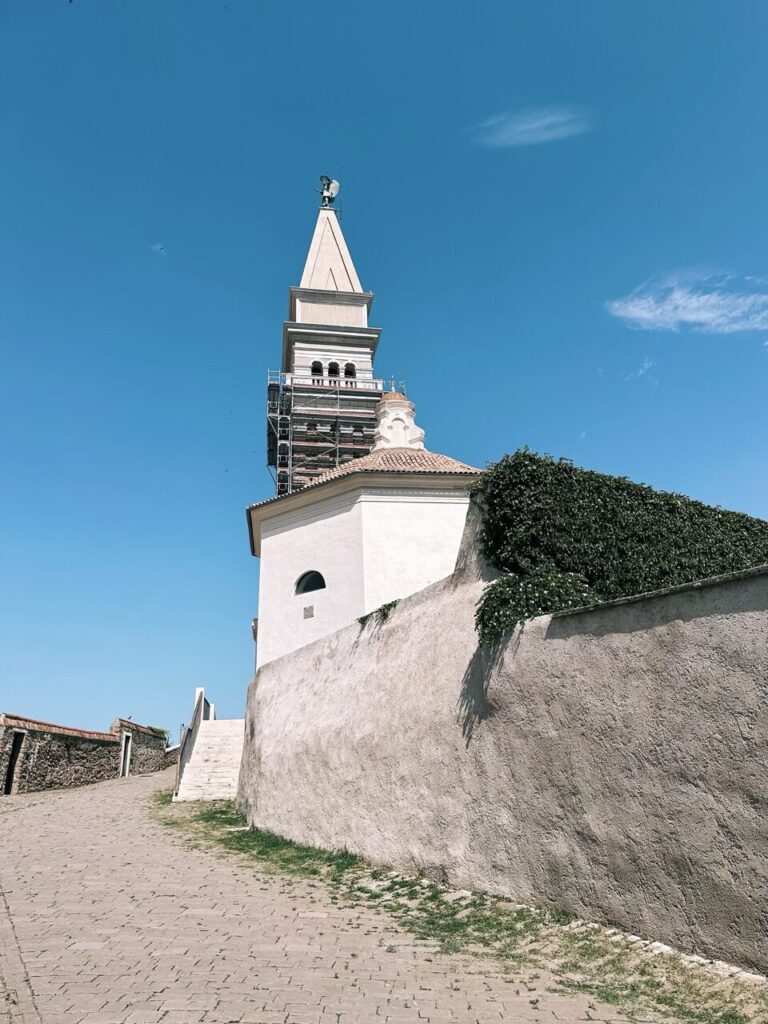 Tall bell tower of a church in Piran under a clear blue sky
