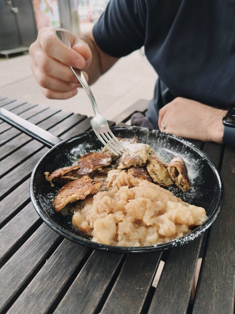 Person eating shredded pancakes and applesauce from a small black skillet