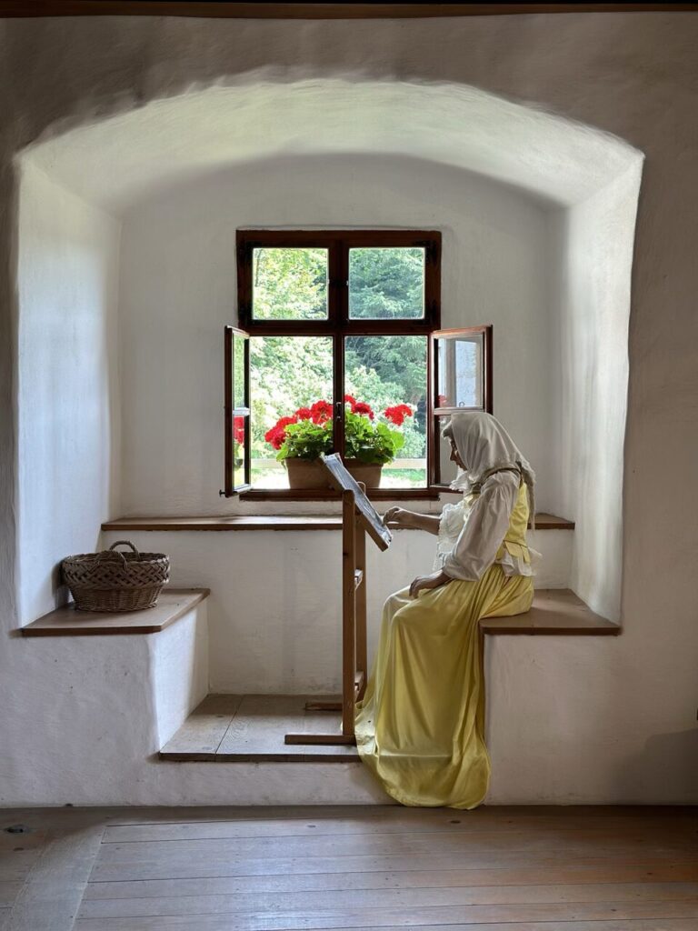 A mannequin in period clothing works at a reading stand inside Predjama Castle