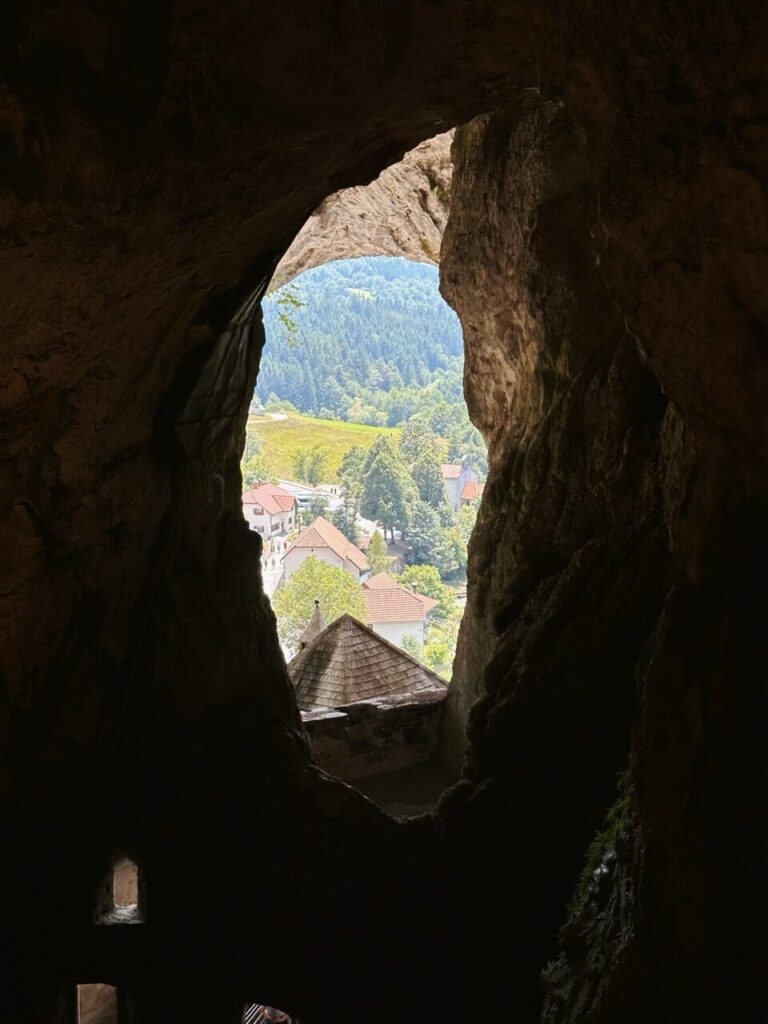 View of a village through a natural opening in Predjama Castle