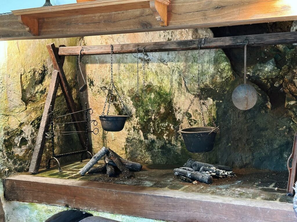 Cast iron pots hang over a fireplace inside Predjama Castle
