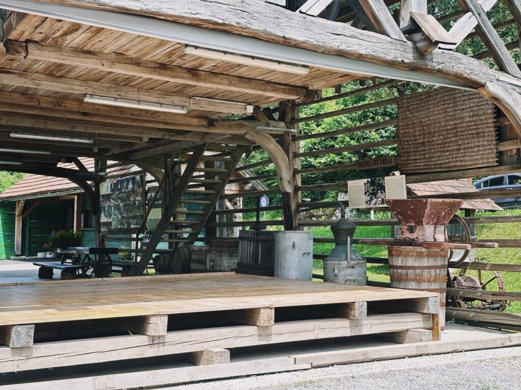 Rustic wooden structure with antique farming equipment and a raised platform in Slovenia
