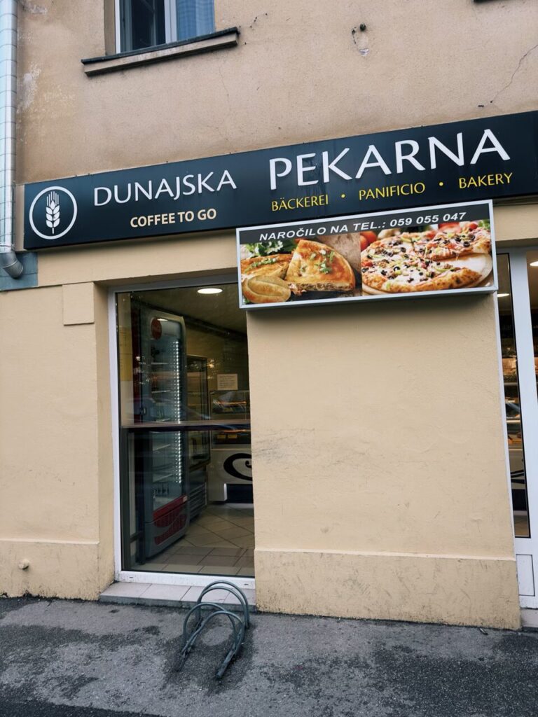 Storefront of a bakery in Slovenia with a sign displaying pizza and pastries