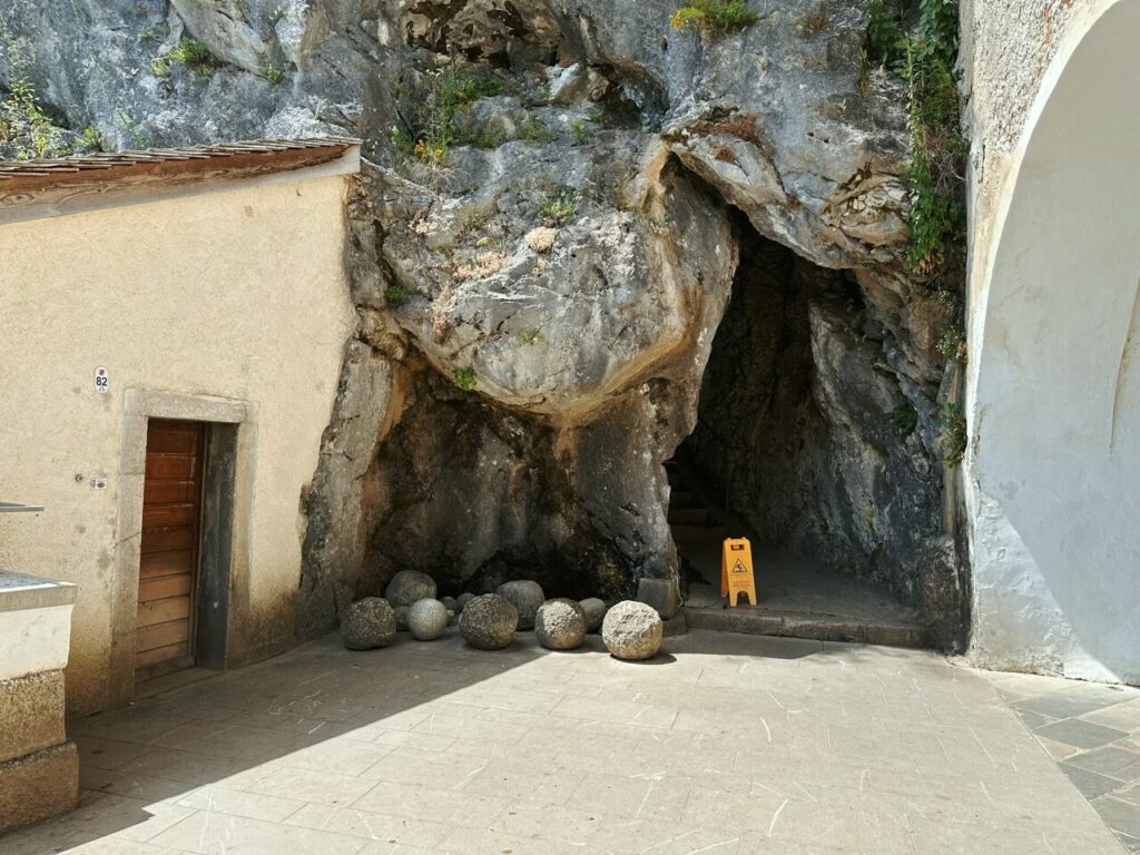 Stone spheres sit before a cave entrance at Predjama Castle