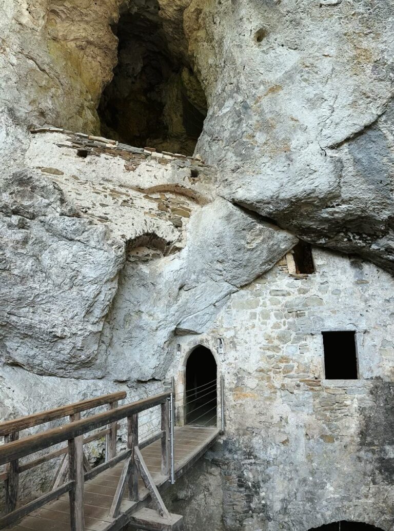 Wooden bridge leading to the stone entrance of Predjama Castle built into rock