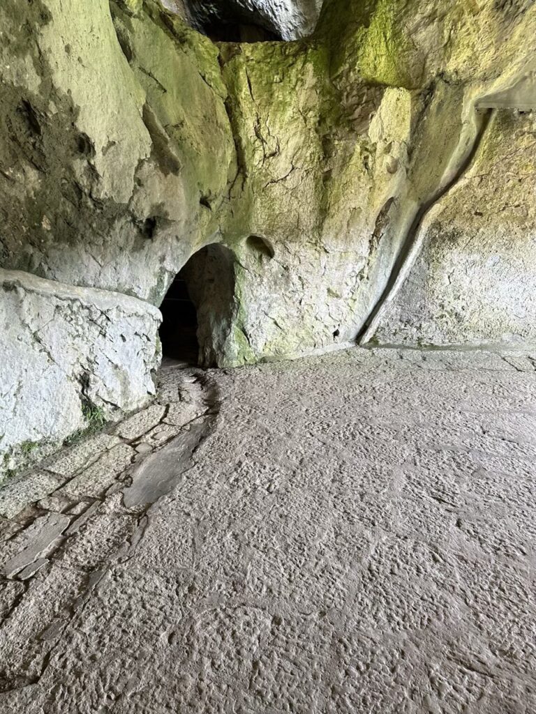Stone path leading into a dark cave opening at Predjama Castle