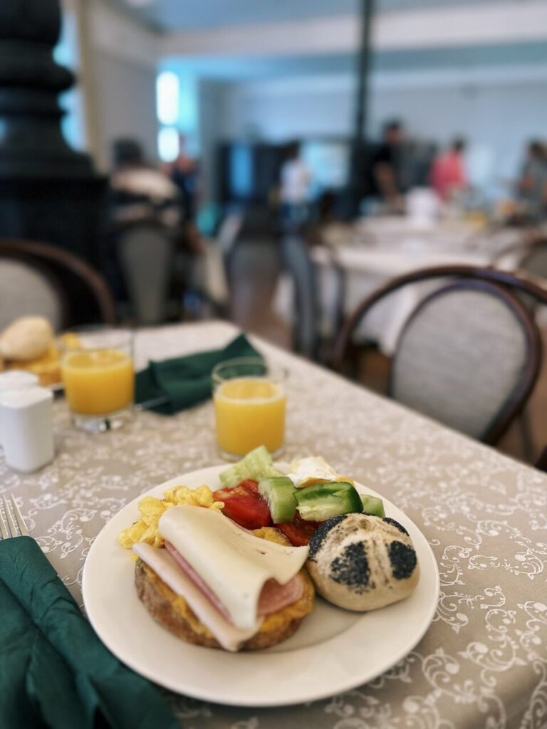 Slovenia road trip breakfast plate with ham, cheese, scrambled eggs, vegetables, and poppy seed roll