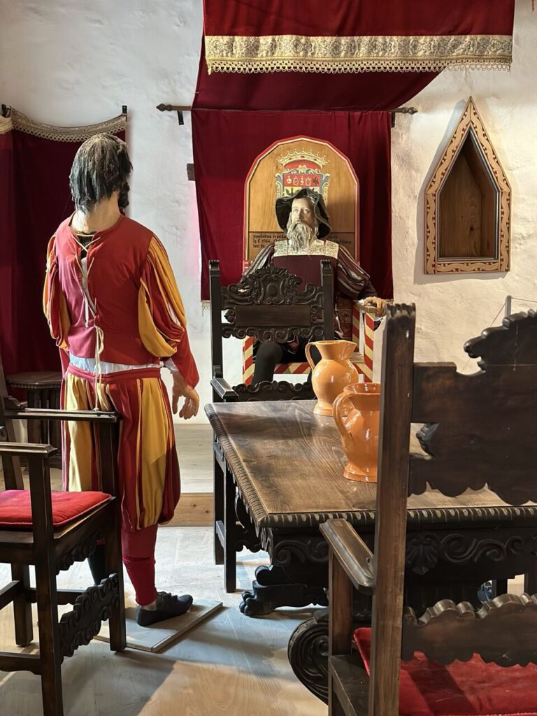 Two medieval mannequins, one standing and one sitting, inside Predjama Castle