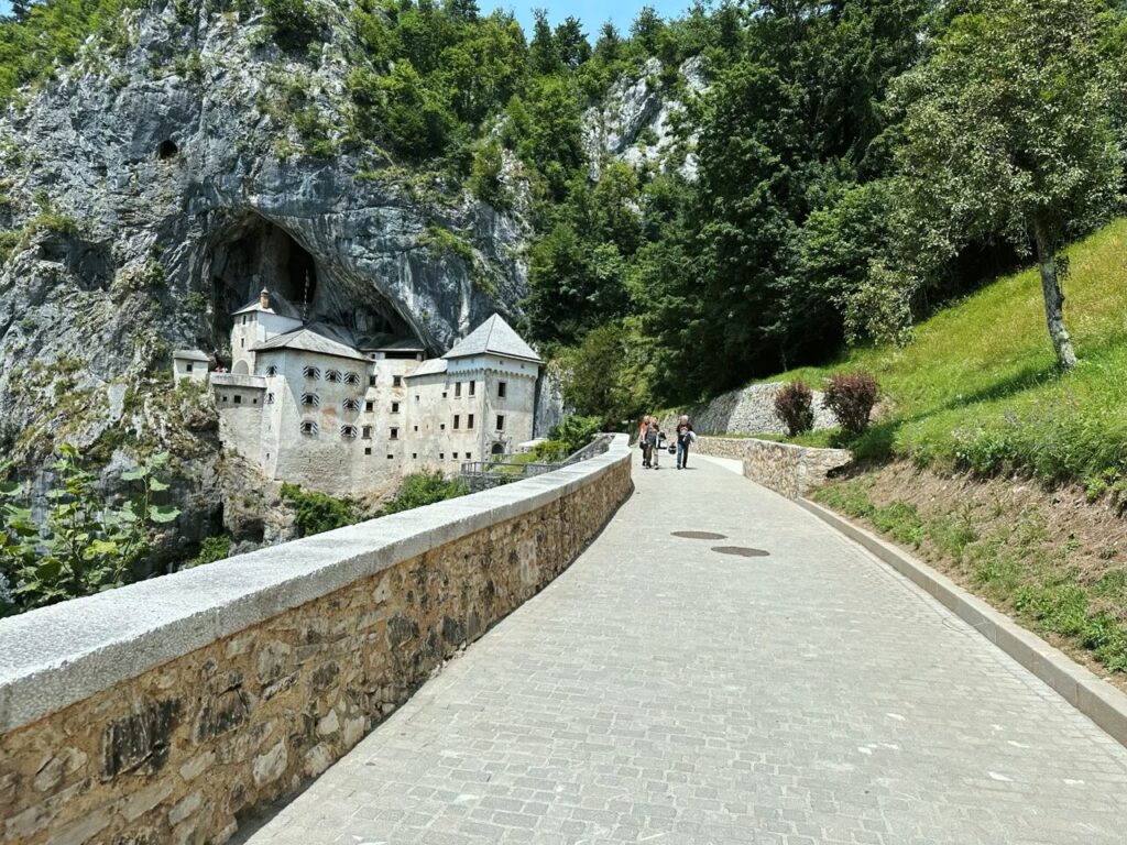 Predjama Castle built into a cliff face, viewed from a paved stone pathway