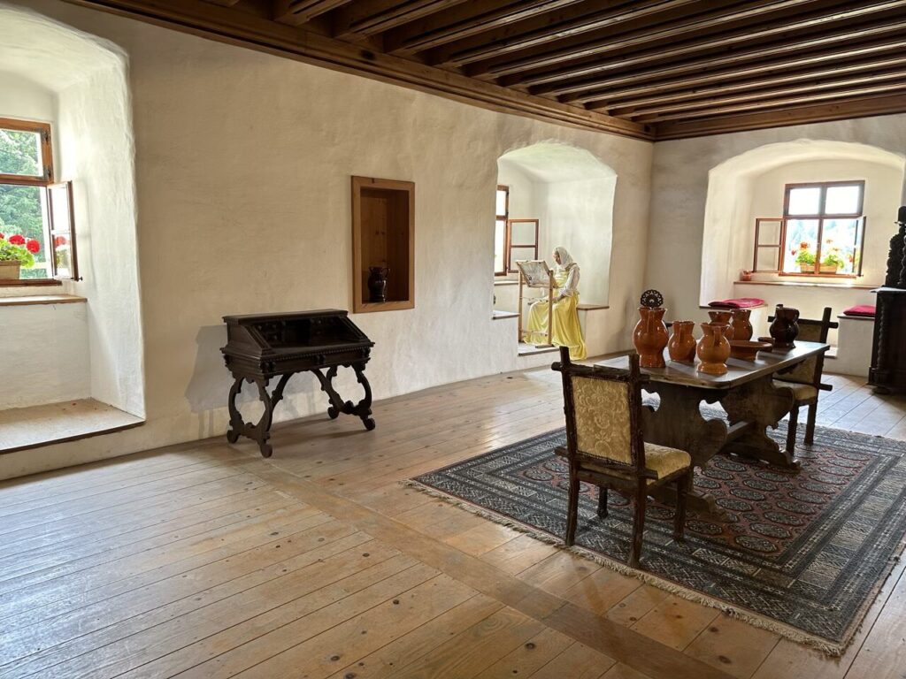 Historical room inside Predjama Castle featuring antique furniture and a mannequin at a loom
