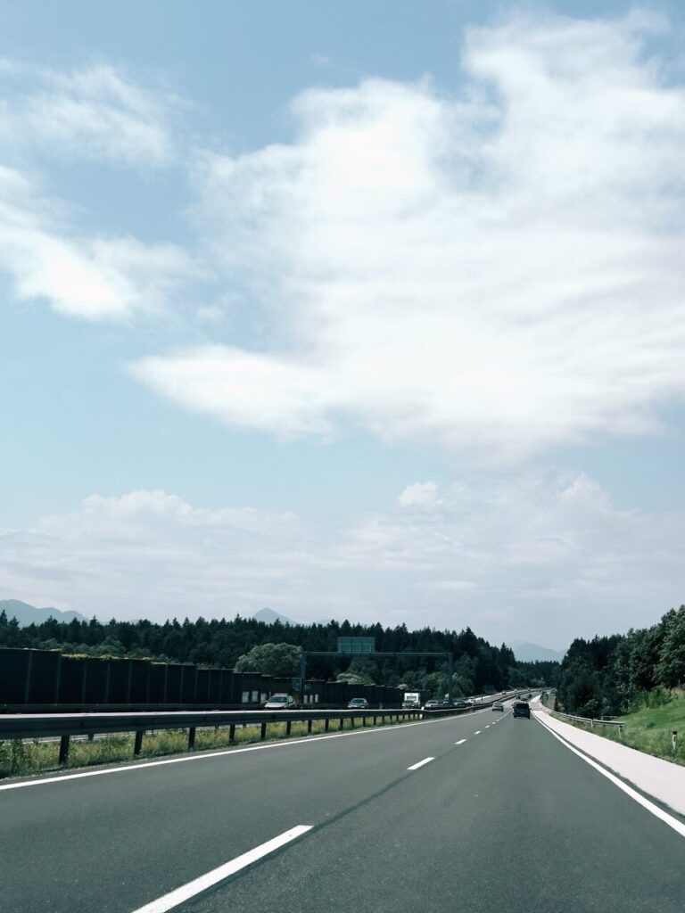 Cars drive along a highway in Slovenia under a cloudy blue sky