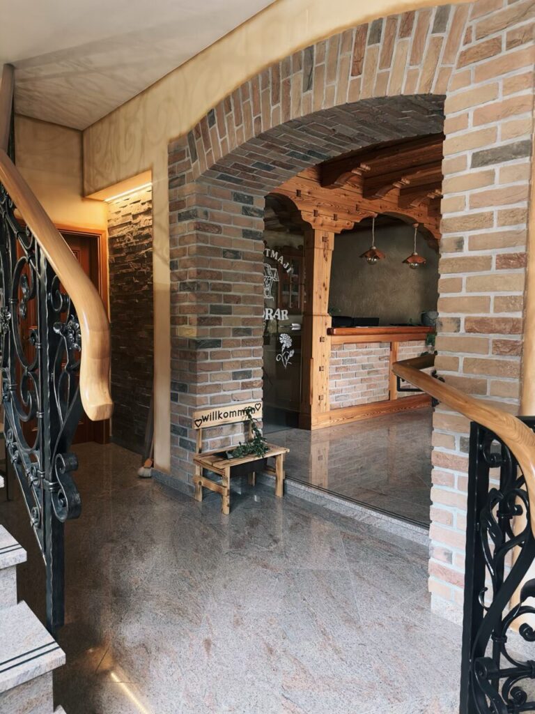 Small wooden bench with a welcome sign inside a rustic brick building