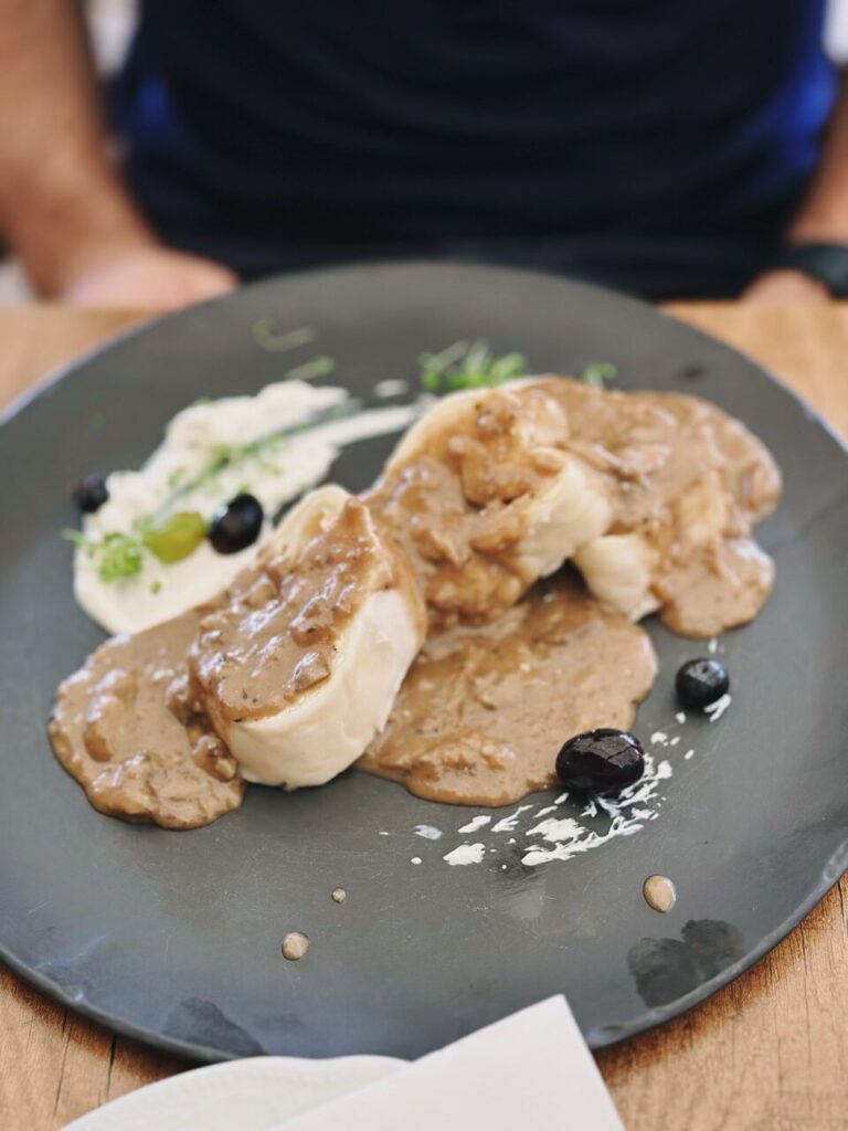 Slovenia rolled dumplings in brown sauce served with white puree and black olives